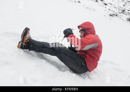 In inverno la formazione di competenze in Cairngorm montagne prima neve viaggio di foratura Andy dimostrando uso di piccozza per impedire una slitta ©Paolo Glendell Foto Stock
