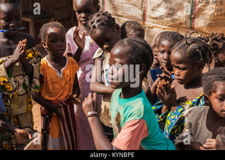 Giovane ragazza africana di eseguire il mosi danza tradizionale chiamato 'warba' mentre i suoi compagni sono mani che applaudono, Ouagadougou, Burkina Faso, Africa. Foto Stock