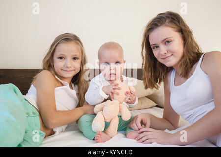 Le tre sorelle Baby girl i bambini al mattino sul letto in camera da letto Foto Stock