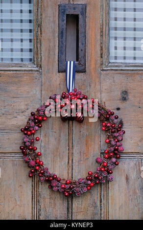 corona di natale di bacche rosse appesa sulla vecchia porta di legno, norfolk, inghilterra Foto Stock