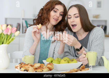 Due femmina sorridente amici seduti a tavola Foto Stock