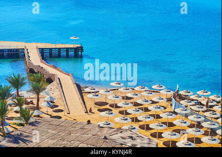 Le file di ombrelloni di paglia su una spiaggia di sabbia accogliente, situato sulla spiaggia di El Maya Bay a Sharm El Sheikh, Egitto. Foto Stock