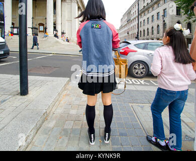 Londra, Inghilterra, Regno Unito. Giovane donna giapponese visto dal retro, in attesa di attraversare la strada in Trafalgar Square Foto Stock