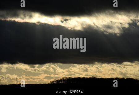 Il sole splende attraverso le nuvole scure vicino a Corby nel Northamptonshire, su ciò che è rivendicato per essere più deprimenti giorno dell'anno. Foto Stock