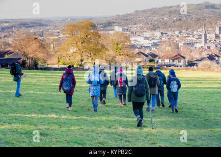 Un gruppo di escursionisti su un luminoso giorno d'inverno passeggiate attraverso il National Trust park verso la città storica di Bath con i suoi edifici in stile georgiano in vista Foto Stock