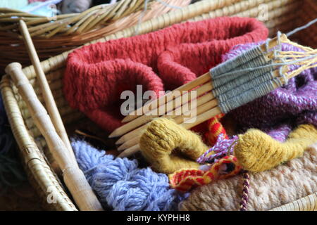 La lana o le sfere di filati e aghi di tessitura, in un tradizionale artigianato in vimini cesto Foto Stock