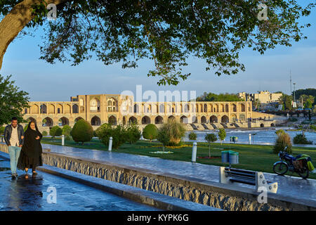 Isfahan, Iran - 24 Aprile 2017: donna musulmana in un chador islamico passeggiate con il braccio con un giovane uomo sorridente sull argine del fiume Zayandeh, vicino Foto Stock