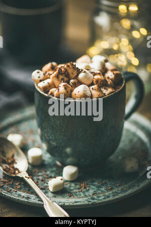 Riscaldamento invernale dolce bere cioccolata calda con marshmallows e cacao in tazza con vacanze di Natale luci dietro, il fuoco selettivo Foto Stock