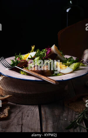 Insalata di patate con cipolla marinted, uova e grano di senape. Vecchio sfondo di legno. Foto Stock