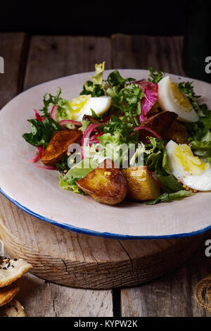 Insalata di patate con cipolla marinted, uova e grano di senape. Vecchio sfondo di legno. Foto Stock