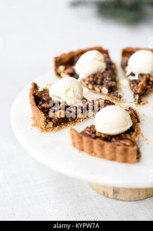 Dado di caramello Tart fette, ciascuna condito con un cucchiaio di gelato Foto Stock