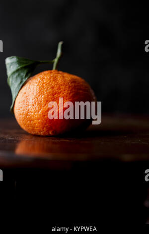 Un satsuma su sfondo scuro Foto Stock