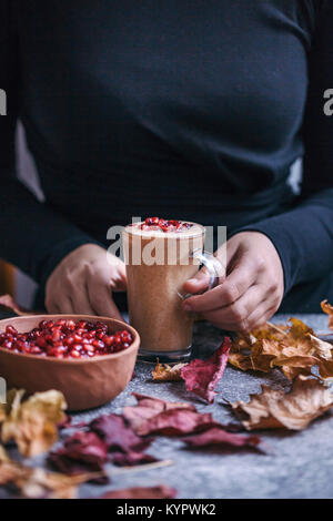 Donna di mangiare banane burro di mandorle smoothie condito con i semi di melograno Foto Stock