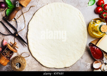 Pizza vegetariana ingredienti: Materie impasto per pizza, olio d'oliva, pomodori e cipolla e le foglie di basilico sulla vecchia superficie di pietra , vista dall'alto. Foto Stock