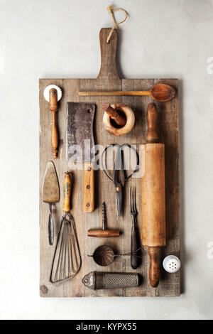 Vista dall'alto di un gruppo di vintage utensili di cottura su un legno tagliere. Foto Stock