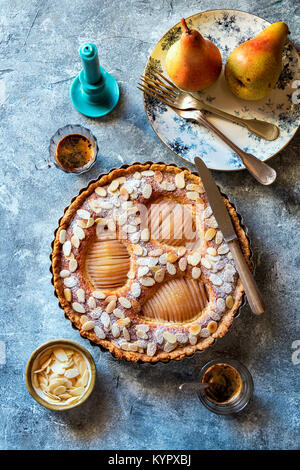 Frangipane Crostata di pere cosparso con mandorle tostate in scaglie con due tazze di caffè sul tavolo Foto Stock