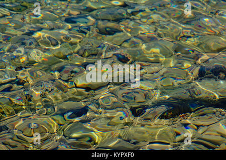 Acqua trasparente con superficie soft increspature che riflette il sole e i ciottoli con il grigio pietra vulcanica sul fondo del mare Adriatico in Mali Losinj, Foto Stock