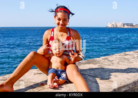 L'Avana, Cuba, 11 maggio 2009. Una donna con il suo bambino seduto sul bordo della parete di Malecon beach boulevard a l'Avana, Maggio 11th, 2009. Foto Stock