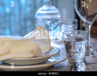 Elegante set di tavolo per pranzare in un estate con bianco piatti di porcellana, bianco vintage tovagliolo in pizzo e vetreria