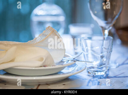 Elegante set di tavolo per pranzare in un estate con bianco piatti di porcellana, bianco vintage tovagliolo in pizzo e vetreria Foto Stock