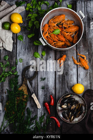 Vista dall'alto di aragoste e cozze in padelle e agrumi con erbe su tavola in legno rustico Foto Stock