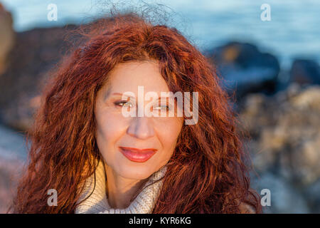 Donna in menopausa con rame rosso e capelli sun-illuminato volto sorridente Foto Stock