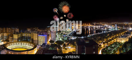 Esterno luminoso vista incandescente città di Malaga in notturna frizzante con fuochi d'artificio al di sopra degli edifici Foto Stock