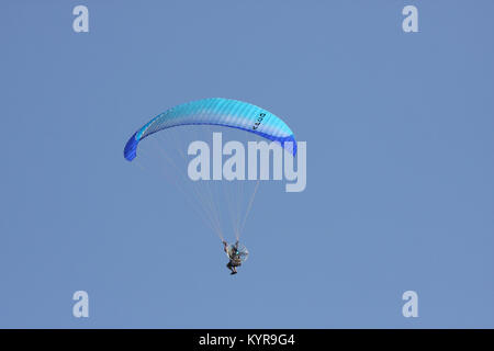 Un parapendio vola nel cielo blu. Il parapendio o paramotoring è una forma di aviazione ultraleggera il pilota sospeso sotto un baldacchino con un motore sul suo b. Foto Stock