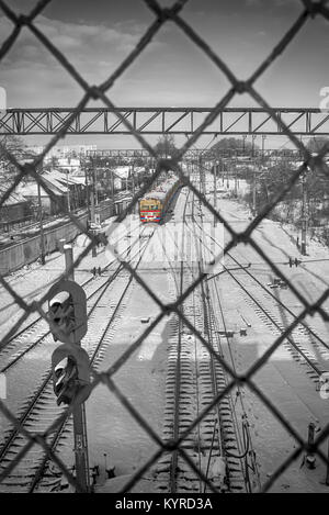 Vedendo un treno e le vie attraverso una sicurezza di rete metallica Foto Stock