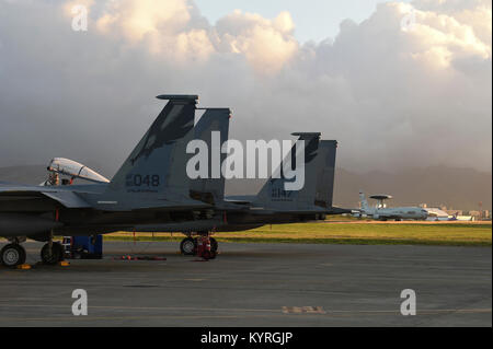Stati Uniti Air Force F-15C Eagle jet da combattimento dal California Air National Guard's 144Fighter Wing pronti per la mattina la missione come una E-3 Sentry AWACS dall'Air Force della riserva di aria 513th gruppo di controllo i taxi da durante la sentinella 18-01 Aloha a base comune Harbor-Hickam perla, Hawaii gen. 11, 2018. Sentry Aloha fornisce conveniente e su misura e realistica di addestramento al combattimento PER GLI STATI UNITI Air Force, Air National Guard e altri per il Dipartimento della difesa dei servizi per fornire warfighters negli Stati Uniti con le competenze necessarie per eseguire i loro homeland defence e oltremare delle missioni di combattimento. (Air National Guard Foto Stock
