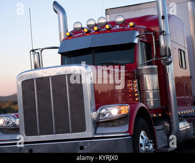 Potente Classic American pro big rig semi carrello in rosso scuro lucido con griglia, ad elevato tenore di cromo tubi e accessori per il trasporto di dry van semi rimorchio Foto Stock