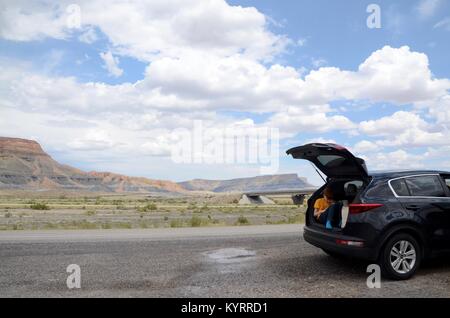 Dai capelli rossi boy siede nell'aprire il tronco di una Kia Sportage sul ciglio della strada in Utah STATI UNITI D'AMERICA Foto Stock