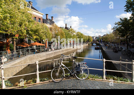 Un biciclette parcheggiate su un ponte su un canale in Leeuwarden, Paesi Bassi. Gli alberi lungo le strade verso il basso il lato del canale. Foto Stock