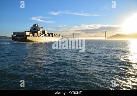 Contenitore nave NYK costellazione lascia San Francisco Bay sotto il Golden Gate Bridge verso il tramonto. Foto Stock