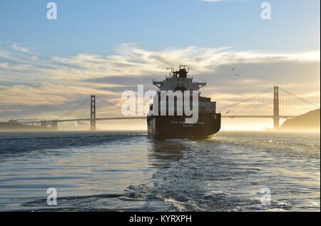 Contenitore nave NYK costellazione lascia San Francisco Bay sotto il Golden Gate Bridge verso il tramonto.