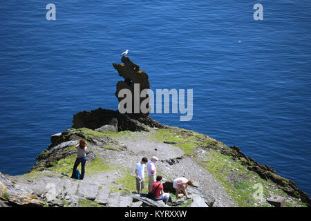 Visitatori stand su Skellig Michael (star wars)affacciato sulla ripida scogliera al di sotto del bordo della contea di Kerry, Irlanda Foto Stock