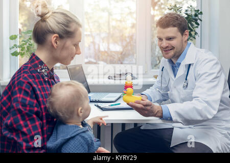 Medico dà al bambino un giocattolo di anatra durante una visita medica Foto Stock