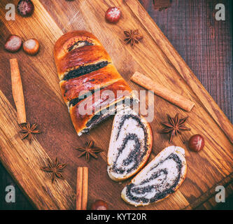 Rotolo al forno con semi di papavero su una tavola di legno, vista dall'alto Foto Stock