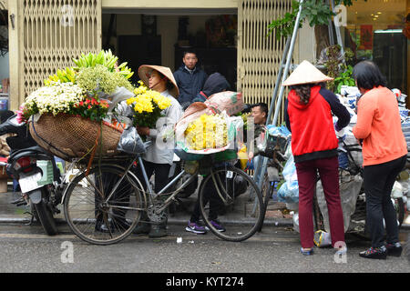 Hanoi, Vietnam - 13 dicembre 2017. Un venditore ambulante che vende i fiori freschi dal retro della sua bici nel vecchio centro storico di Hanoi Foto Stock