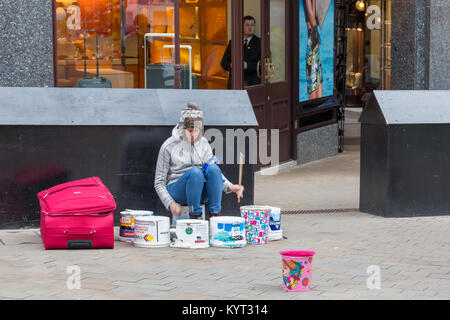 La donna per le strade di Leeds giocando falsi tamburi per fare un po' di soldi Foto Stock