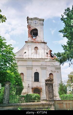 Sunja (Moslavina) in Croazia durante la guerra 1991 - 1995 il villaggio era quasi circondato da truppe serbe e solo raggiungibile tramite traghetto per attraversare il fiume Sava. Il danneggiato la Chiesa cattolica in prossimità della linea anteriore tra la Repubblica di Croazia e la Repubblica serba di Krajina. La foto è stata scattata nel Giugno 1992. In quel momento il villaggio non era abitata. Foto Stock