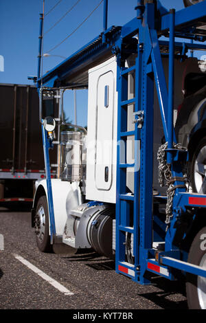 Un classico semplice potente di un bianco luminoso big rig semi un carrello con due livelli di trasportatore auto rimorchio per il trasporto di auto, attrezzata con gli ascensori idraulici Foto Stock