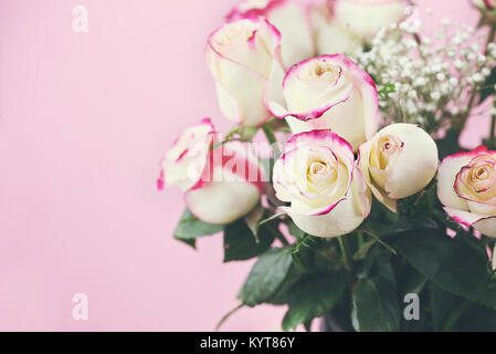 Bel bouquet di rosso e rose bianche con il bimbo di respiro contro un sfondo rosa. Messa a fuoco selettiva su roses in primo piano con estrema shallow de Foto Stock