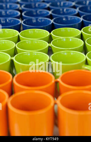 Tazze di ceramica e ciotole di diversi colori nel negozio del contatore, stand in una pila di riga. La vendita e il commercio. Foto Stock