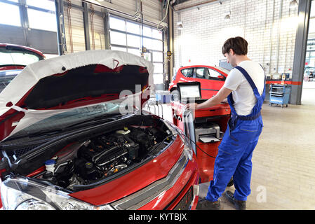 Meccanico ripara motore da un automobile con l aiuto di un computer diagnostico Foto Stock