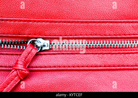 Zipper parzialmente open close up foto di dettaglio su una pelle rossa sullo sfondo di texture. Foto Stock