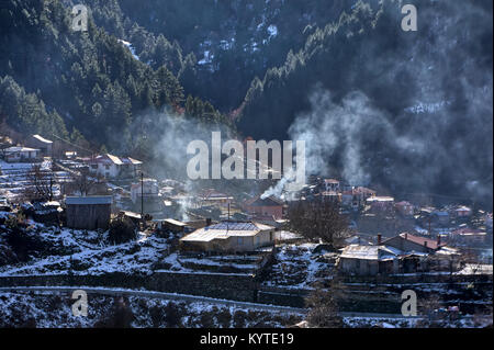 Paesaggio invernale dalla gamma della montagna di Pindo e il villaggio di Distrato con i camini di andare fuori a fumare, Grecia Foto Stock