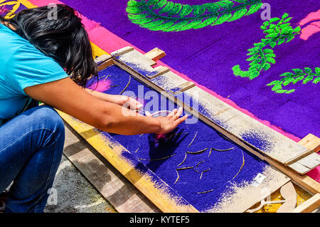 Antigua Guatemala - Marzo 15, 2015: Donna rende la Quaresima segatura colorata processione tappeto in città con più famosi alle celebrazioni della Settimana Santa in America Latina Foto Stock