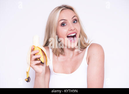 Bella donna bionda di mangiare una banana Foto Stock