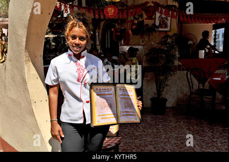 L'Avana, Cuba, 20 ottobre 2009. Un giovane cameriera cubana in una camicia bianca che mostra il menu di un ristorante a l'Avana del Chinatown. Foto Stock